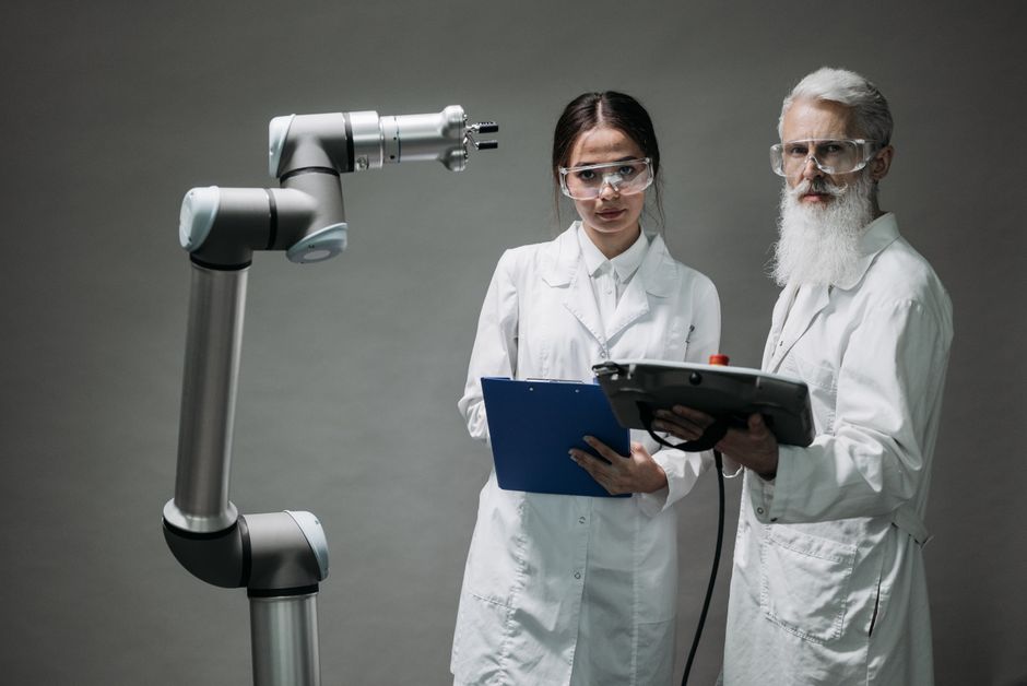 Two scientists in lab coats analyzing a robotic arm in a laboratory setting